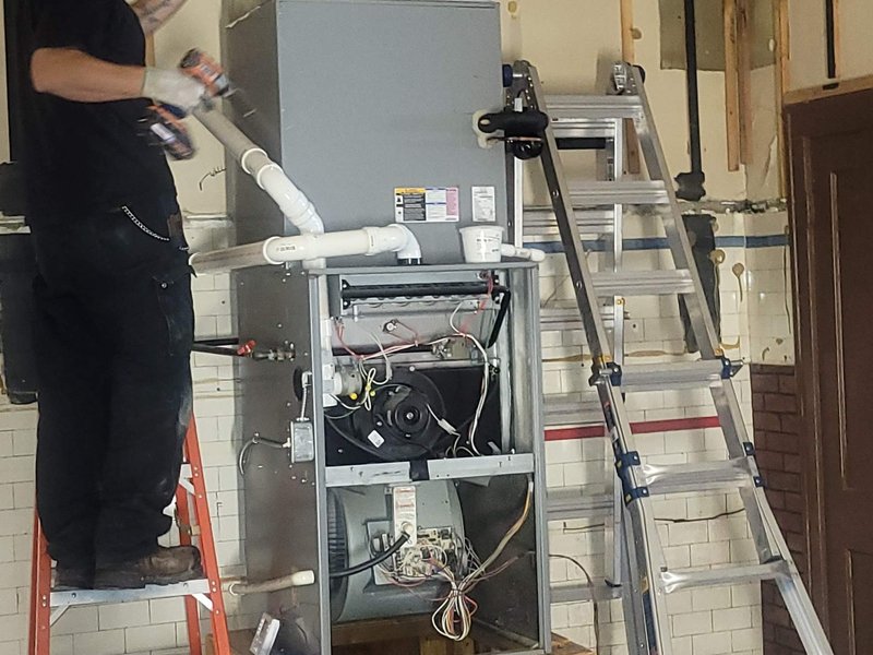 Americool technician repairing a furnace in a basement